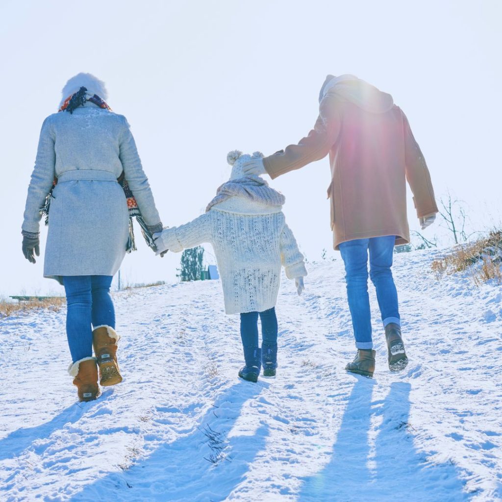 family of three bundled up and hiking in the snow